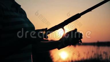 一个年轻女子的剪影，手里拿着一根鱼竿，在黎明时把钓索拉出来